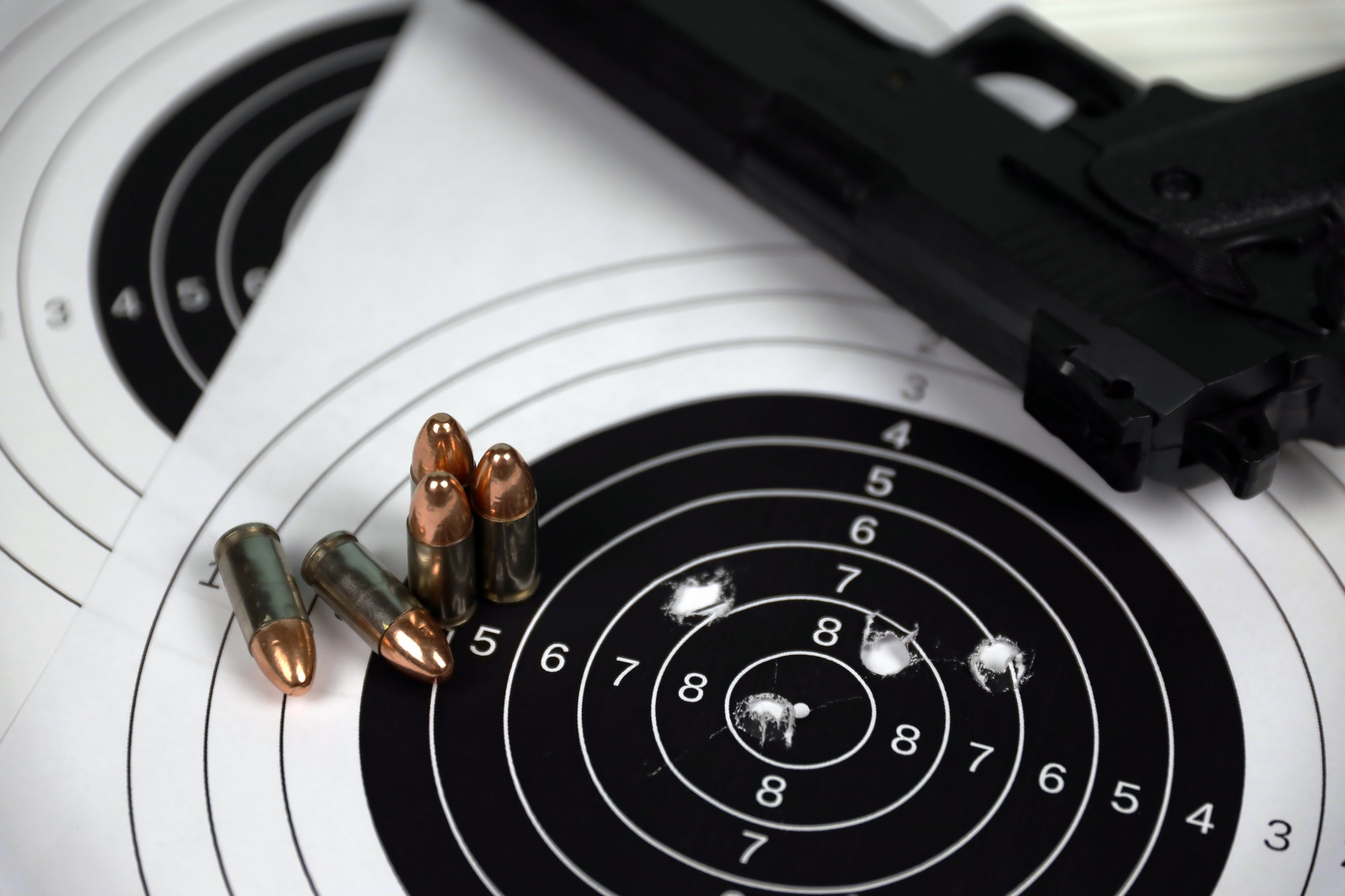 gun-and-many-bullets-shooting-targets-on-white-table-in-shooting-range-polygon-training-for-aiming.jpg